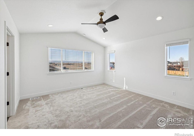 carpeted empty room featuring ceiling fan, a healthy amount of sunlight, and vaulted ceiling