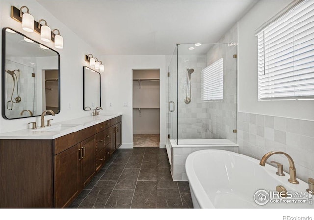 bathroom featuring tile patterned floors, vanity, tile walls, and shower with separate bathtub