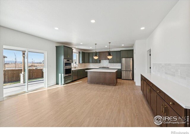 kitchen with backsplash, stainless steel appliances, decorative light fixtures, light hardwood / wood-style floors, and a kitchen island