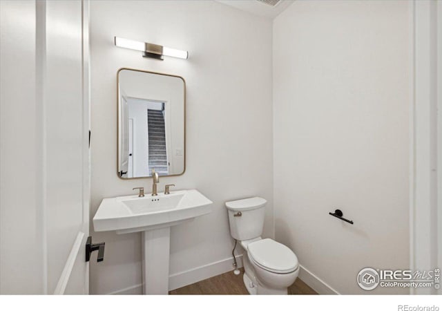 bathroom with hardwood / wood-style flooring and toilet