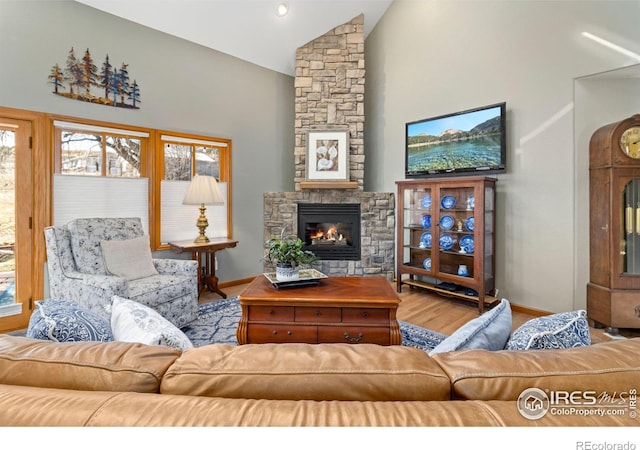 living room featuring light wood-type flooring, a fireplace, and high vaulted ceiling