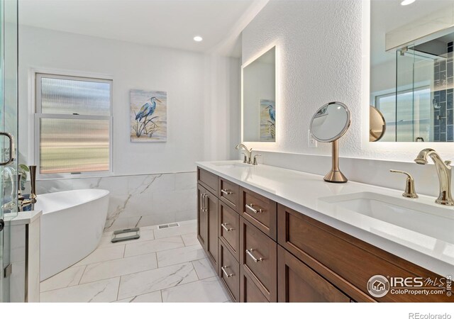 bathroom featuring double sink vanity, a tub to relax in, tile patterned flooring, and a healthy amount of sunlight