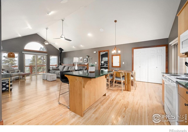 kitchen featuring a breakfast bar, white range with electric cooktop, a kitchen island, light brown cabinetry, and a wood stove