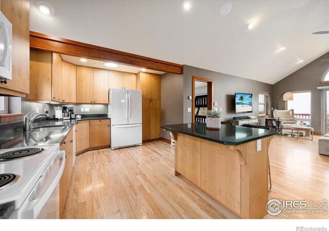 kitchen with a kitchen bar, light brown cabinetry, sink, light wood-type flooring, and white appliances