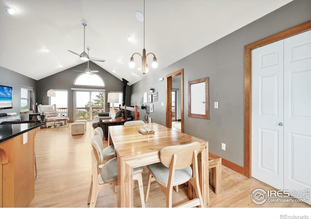 dining area featuring lofted ceiling, ceiling fan with notable chandelier, and light hardwood / wood-style floors