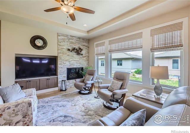 living room with a fireplace, wood-type flooring, and ceiling fan