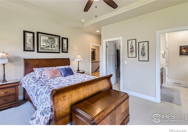 bedroom featuring light carpet, ensuite bathroom, and ceiling fan