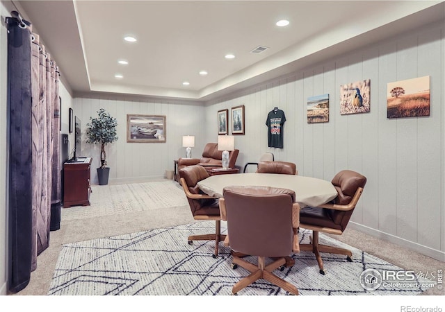 dining area featuring light colored carpet and a raised ceiling