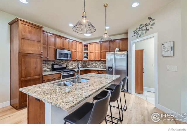 kitchen with tasteful backsplash, pendant lighting, stainless steel appliances, and a kitchen island with sink