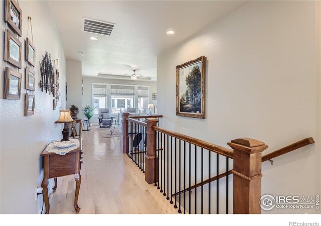 hall with light hardwood / wood-style floors and a textured ceiling