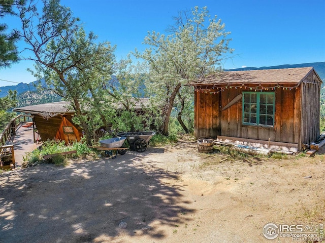 view of side of home with a mountain view and an outbuilding