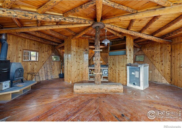 unfurnished living room featuring a wood stove, wood walls, wood ceiling, and hardwood / wood-style flooring