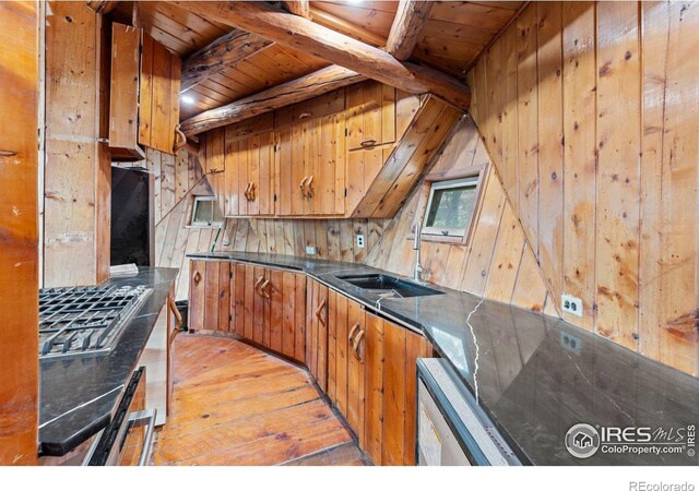 kitchen with sink, beamed ceiling, wood walls, wood ceiling, and light wood-type flooring