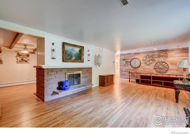 unfurnished living room featuring wood walls, a baseboard heating unit, a stone fireplace, light wood-type flooring, and beam ceiling