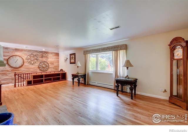 living area featuring baseboard heating and hardwood / wood-style floors