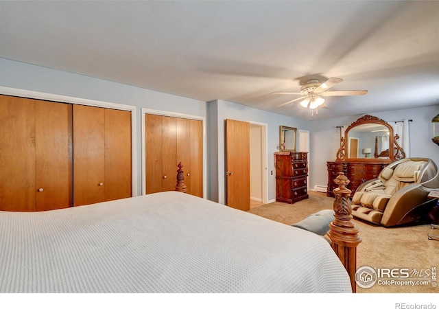 bedroom featuring ceiling fan, light colored carpet, a baseboard radiator, and multiple closets