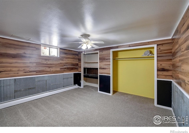 interior space featuring carpet, wood walls, a closet, and ceiling fan