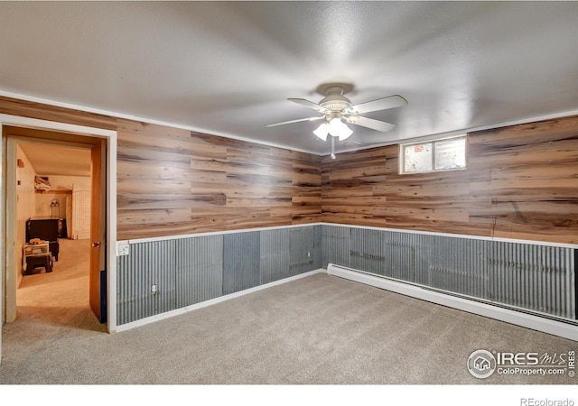 unfurnished room with carpet flooring, ceiling fan, and wood walls