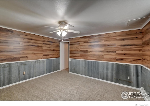 carpeted spare room with ceiling fan and wooden walls