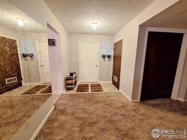 carpeted foyer with a textured ceiling