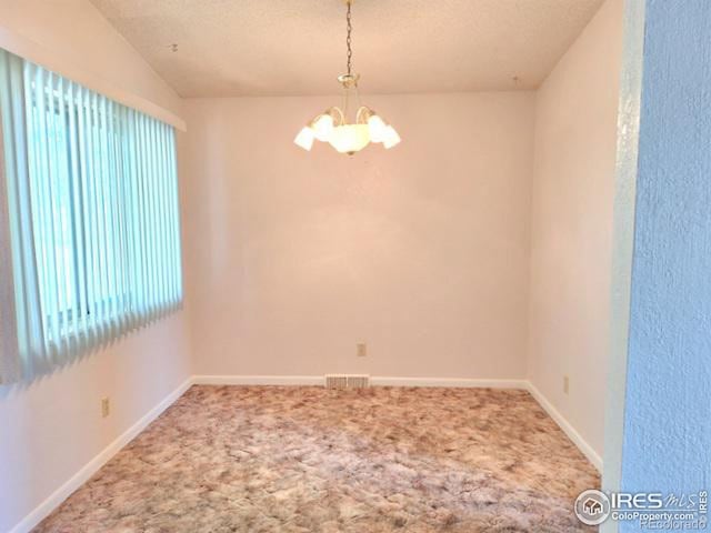 unfurnished room featuring a chandelier