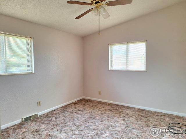 carpeted spare room featuring ceiling fan and a textured ceiling