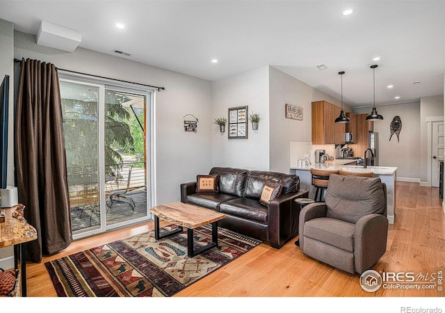 living room with light hardwood / wood-style floors and sink