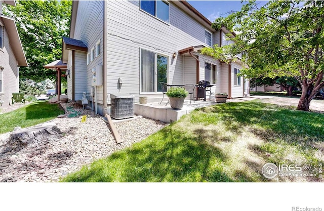 view of side of home featuring a patio, central air condition unit, and a lawn