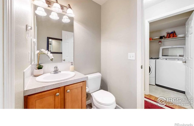 bathroom featuring vanity, washer and dryer, and toilet