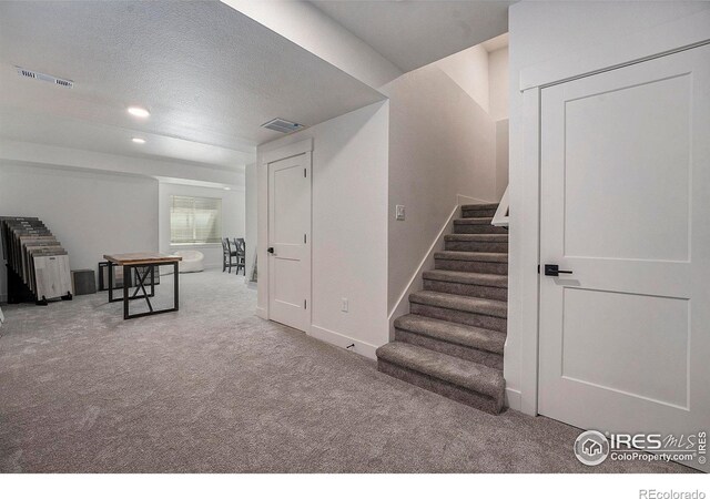 staircase with carpet flooring and a textured ceiling