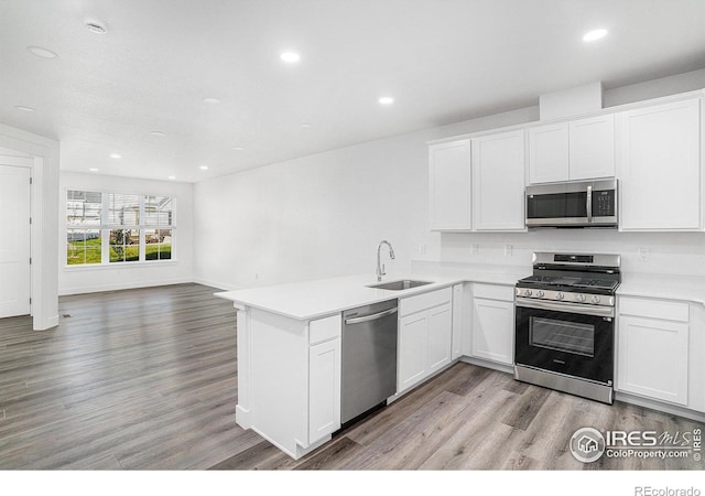 kitchen with sink, white cabinetry, kitchen peninsula, and stainless steel appliances