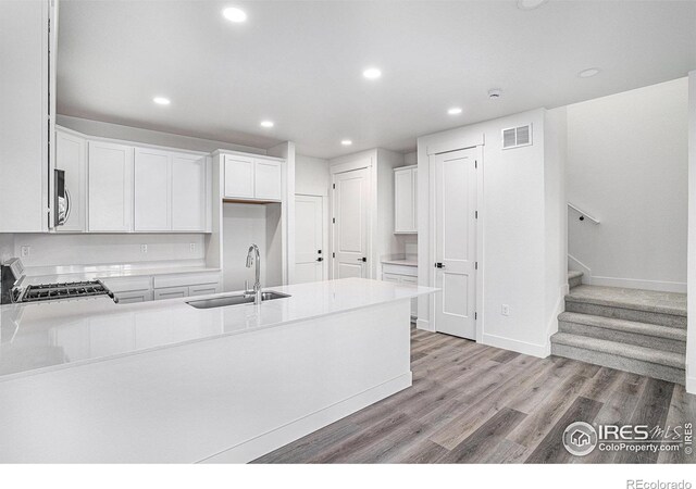 kitchen with sink, appliances with stainless steel finishes, white cabinetry, and light hardwood / wood-style floors