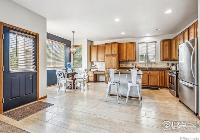 kitchen with pendant lighting, a breakfast bar, a healthy amount of sunlight, and appliances with stainless steel finishes