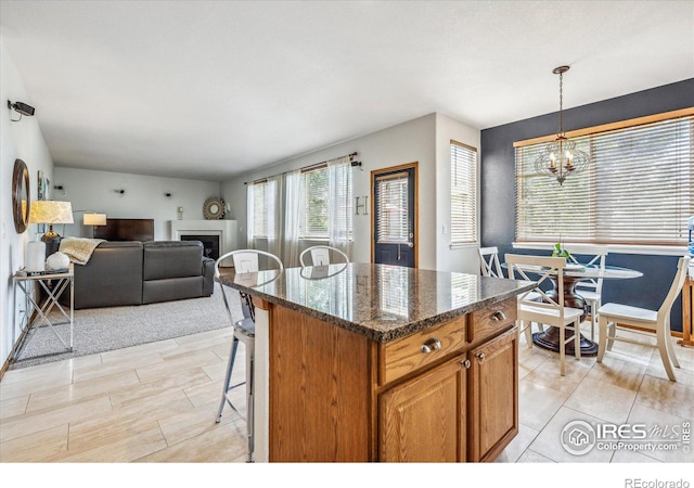 kitchen featuring a kitchen bar, decorative light fixtures, dark stone countertops, a chandelier, and a kitchen island