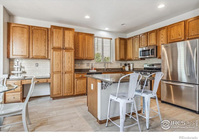 kitchen with sink, a kitchen breakfast bar, dark stone counters, a kitchen island, and appliances with stainless steel finishes