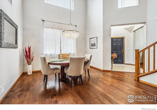 dining area with hardwood / wood-style floors, a chandelier, and a high ceiling