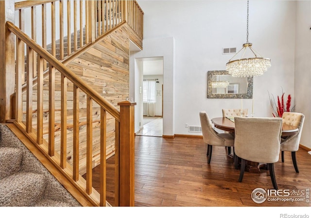 dining space featuring a towering ceiling, hardwood / wood-style flooring, and a notable chandelier