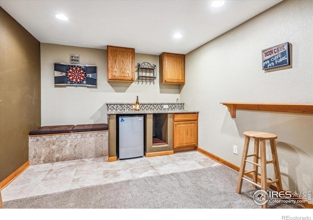 kitchen featuring a breakfast bar area, light carpet, and refrigerator