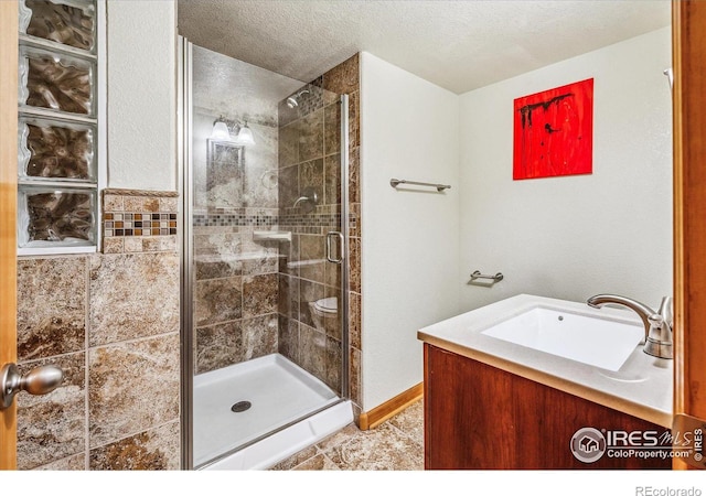 bathroom with a textured ceiling, an enclosed shower, and sink