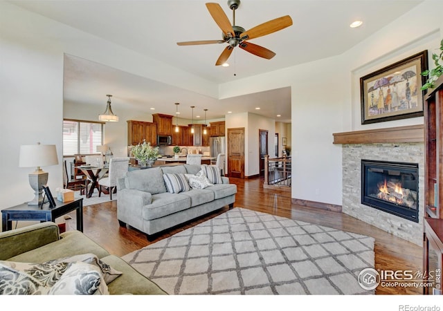 living area with ceiling fan, dark wood-style flooring, a glass covered fireplace, and recessed lighting