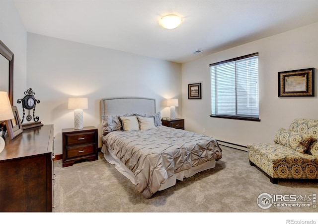 bedroom with a baseboard heating unit, light carpet, and visible vents