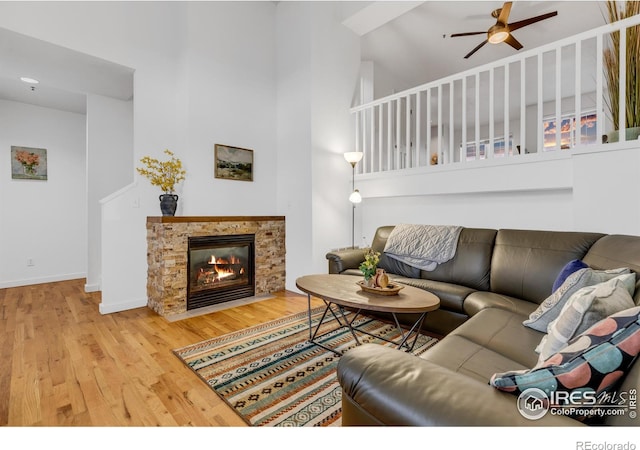 living room with a stone fireplace, a towering ceiling, and hardwood / wood-style flooring