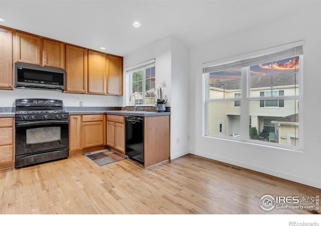 kitchen featuring sink, black appliances, and light hardwood / wood-style flooring