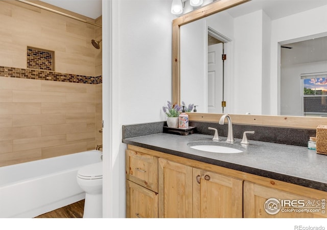 full bathroom featuring toilet, hardwood / wood-style flooring, tiled shower / bath, and vanity