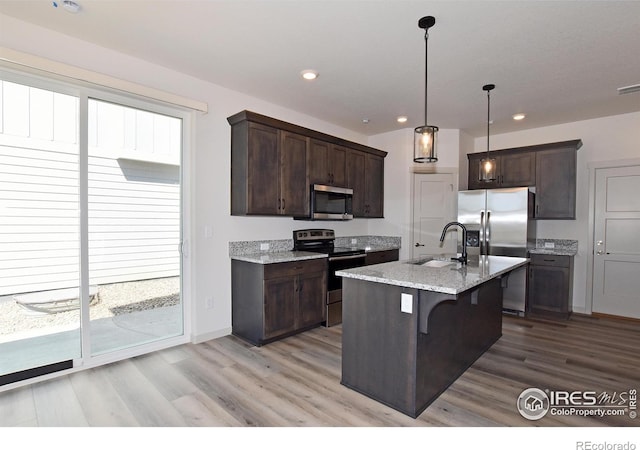 kitchen featuring pendant lighting, sink, a breakfast bar area, appliances with stainless steel finishes, and an island with sink