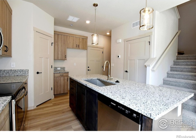 kitchen with light hardwood / wood-style flooring, a center island with sink, dishwasher, decorative light fixtures, and sink