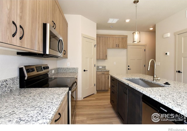 kitchen featuring appliances with stainless steel finishes, sink, light hardwood / wood-style floors, and light stone countertops