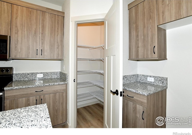 kitchen with wood-type flooring, light stone countertops, and stove