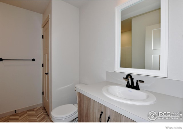 bathroom with parquet flooring, toilet, and vanity