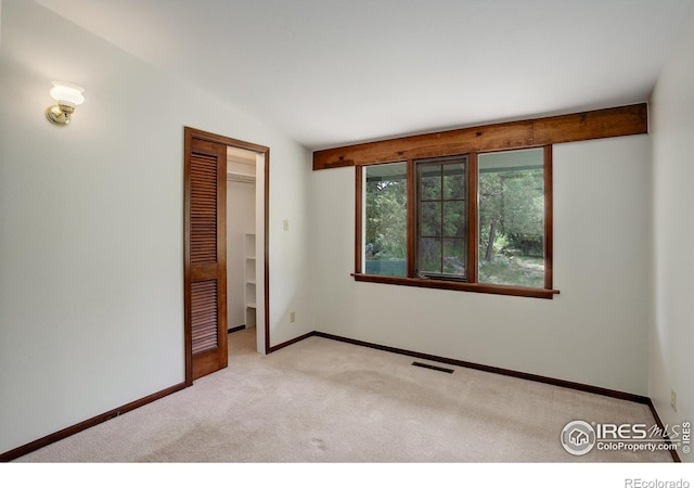 spare room featuring vaulted ceiling and light colored carpet